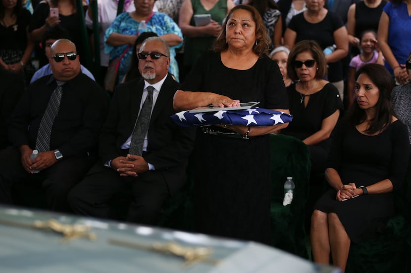 Maria Ramirez, wife of Felix Lozada, stands after military funeral honors during Lozada's...