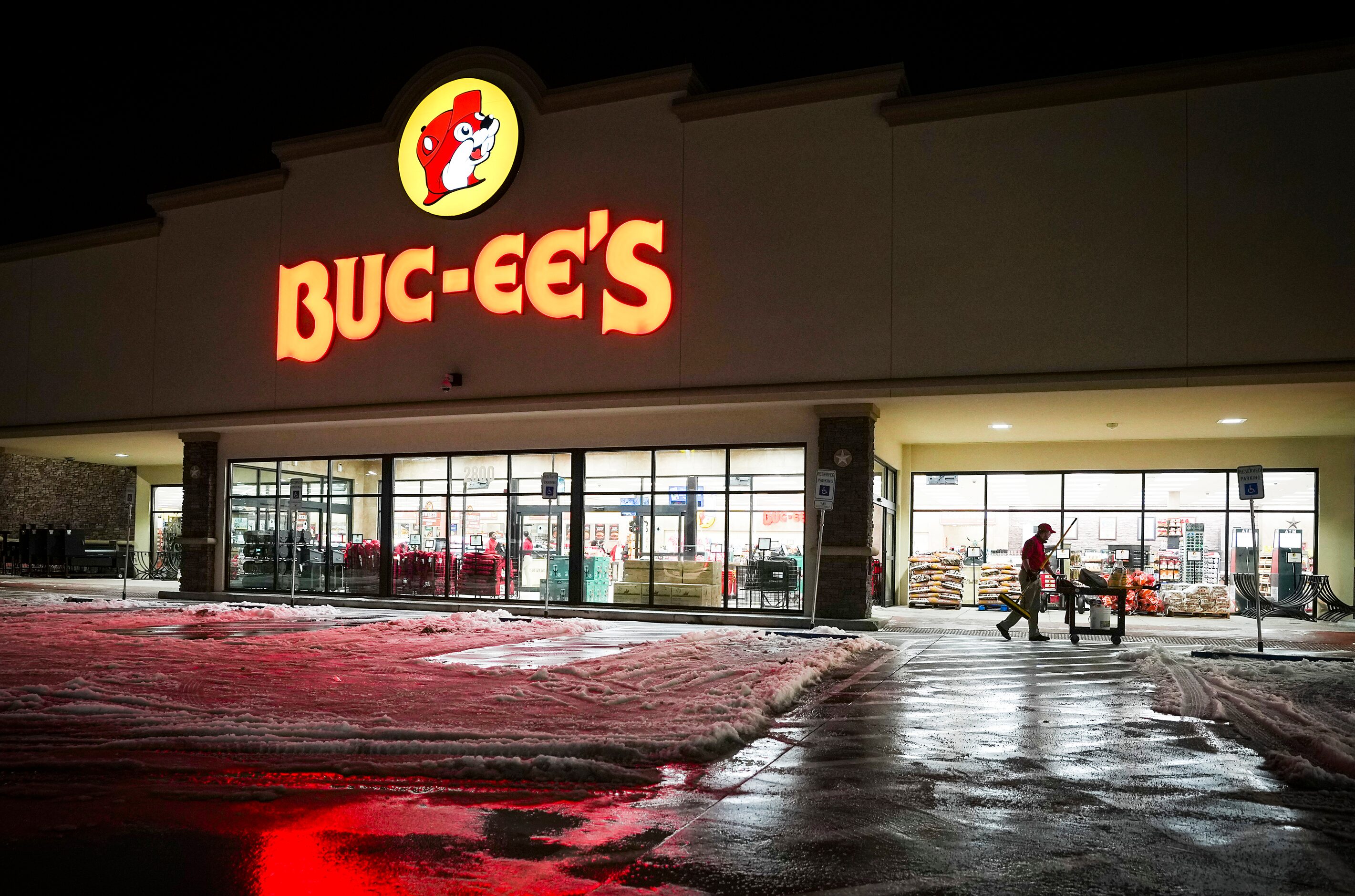 Employee Christopher Scroggins pushes a cart while clearing snow and ice from walkways in...