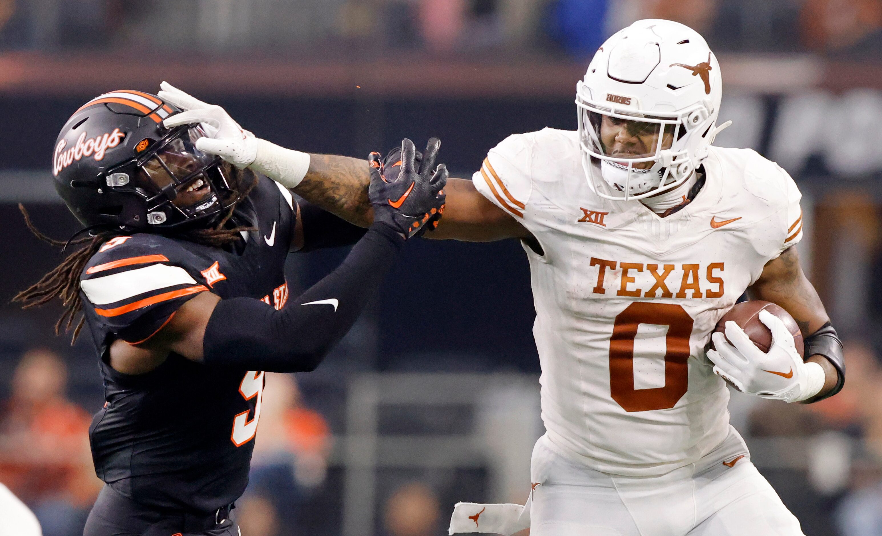 Texas Longhorns tight end Ja'Tavion Sanders (0) gives a stiff arm to Oklahoma State Cowboys...