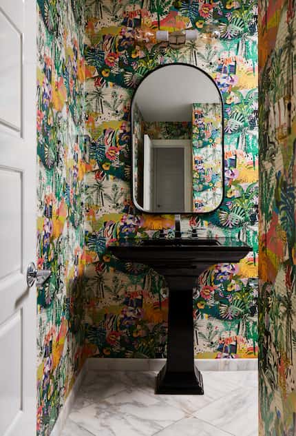 A powder bathroom features a black sink and bold wallpaper.