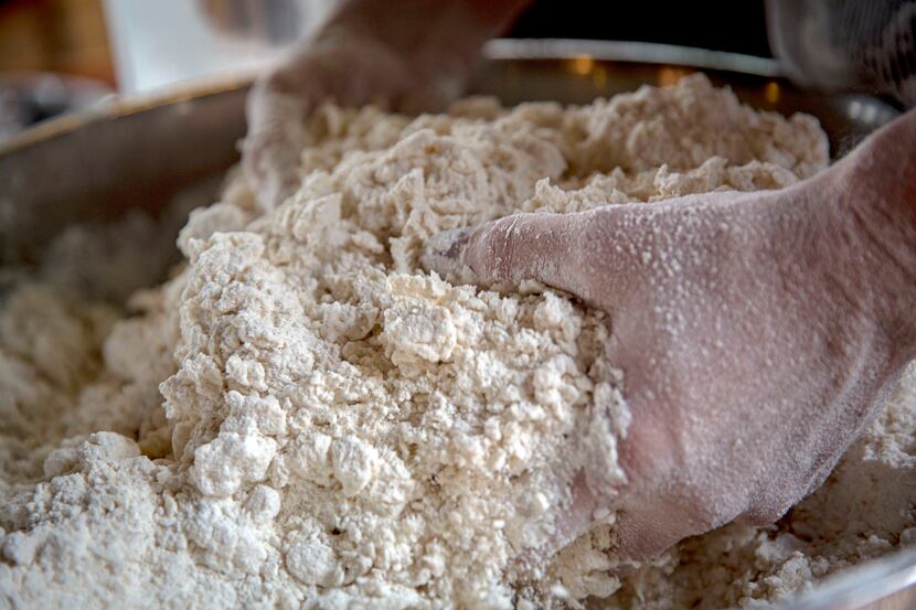 Chef Tim Byres mixes heavy cream with dry ingredients as he prepares buttermilk biscuits at...