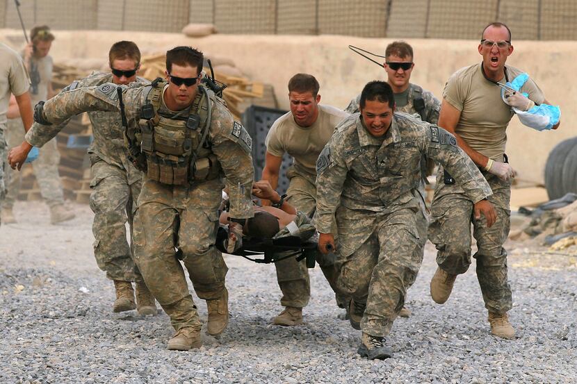U.S. Army soldiers carry a critically wounded American soldier on a stretcher to an awaiting...