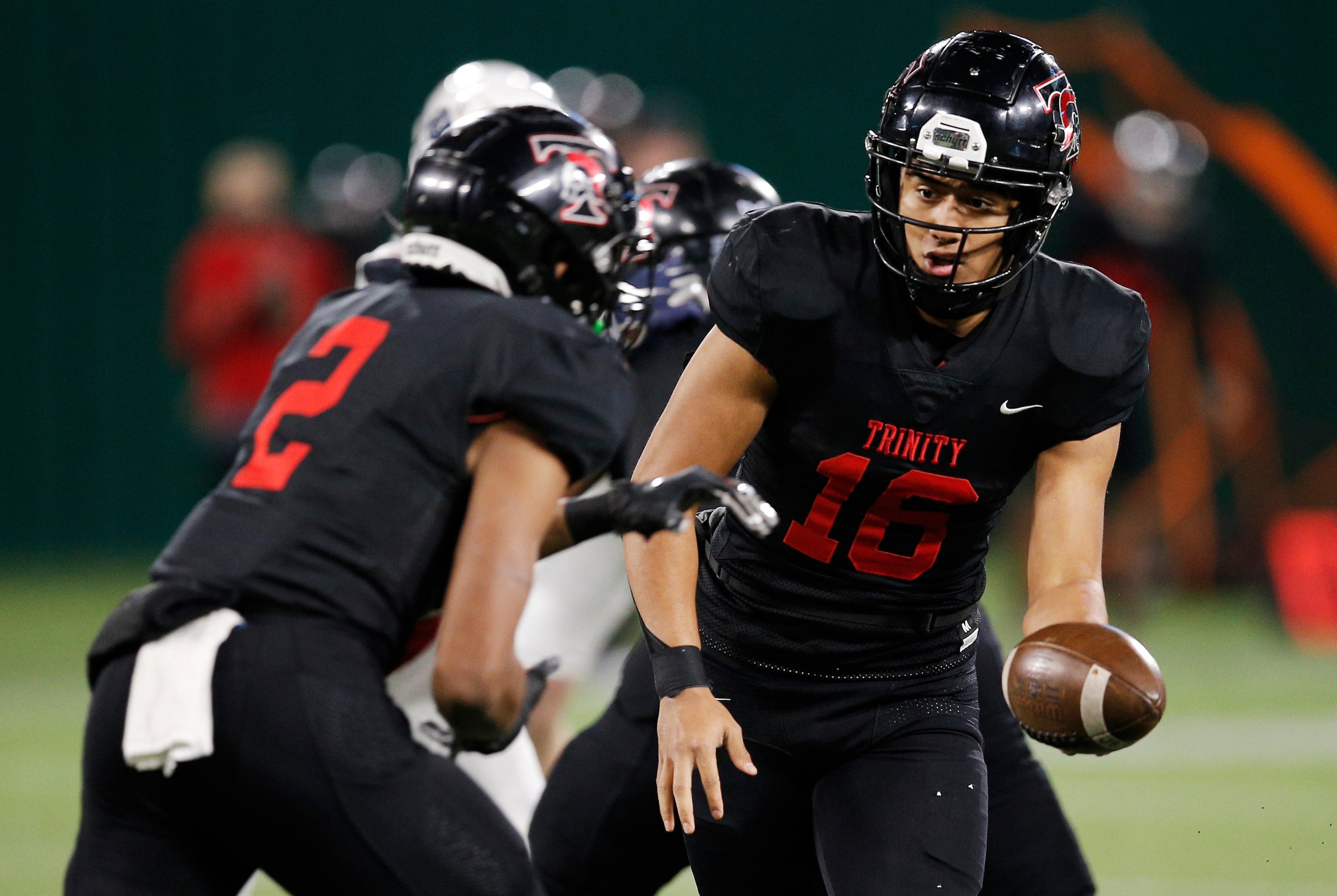 Euless Trinity senior quarterback Valentino  Foni (16) hands the ball off to junior running...