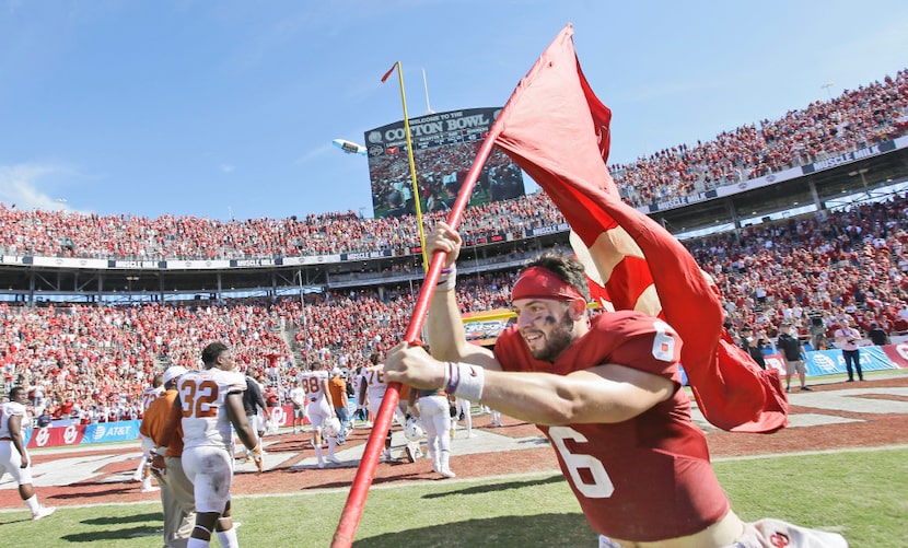 Oklahoma quarterback Baker Mayfield (6) runs on the field with a school flag after 45-40 win...