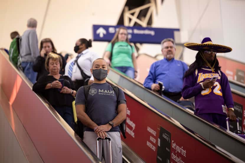 Travelers take the escalator down from the Skylink on May 6 at DFW International Airport.
