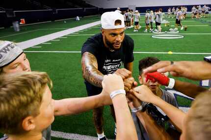 Cowboys quarterback Dak Prescott huddles with students while running drills during the Tom...