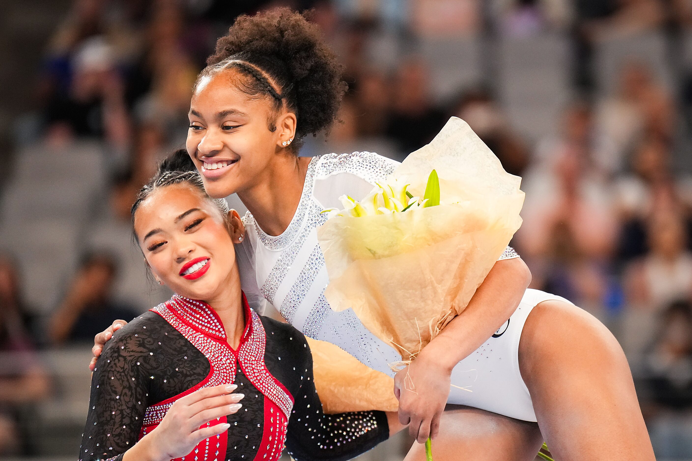 Silver medalist Skye Blakely (right) hugs fourth place finisher Sunisa Lee on the podium...