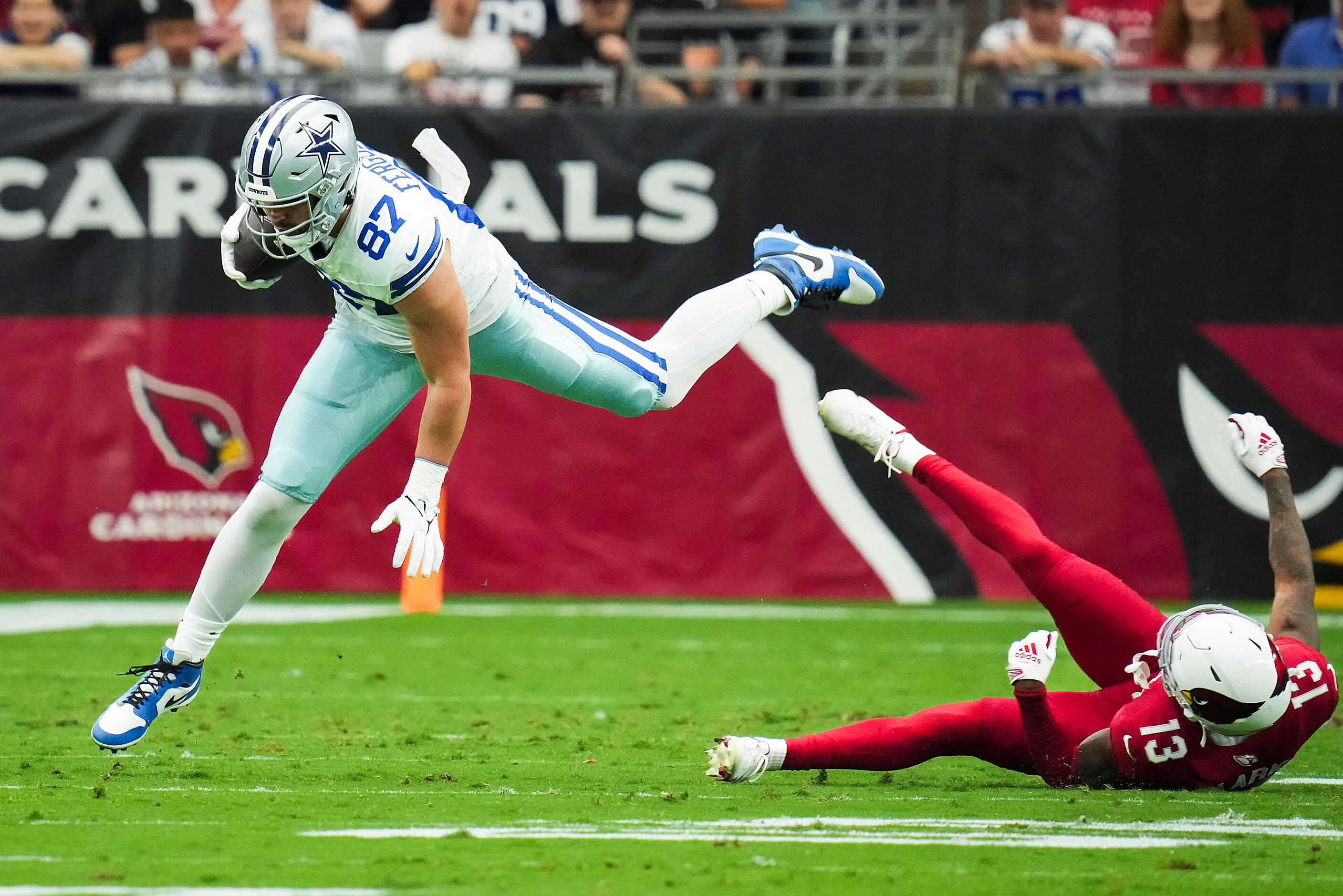 Dallas Cowboys tight end Jake Ferguson (87) is tripped up by Arizona Cardinals cornerback...