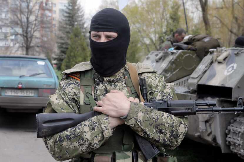 A masked gunman guards combat vehicles parked in downtown Slovyansk, Ukraine, on Wednesday,...