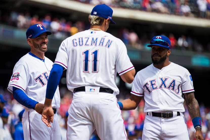 Texas Rangers manager Chris Woodward (8) and center fielder Delino DeShields (3) greet first...