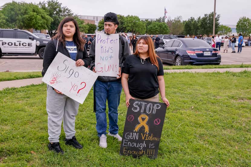 Melany Lopez, 17 (from left), Christopher Leon, 17, and Steisy Montero, 16, hold signs...