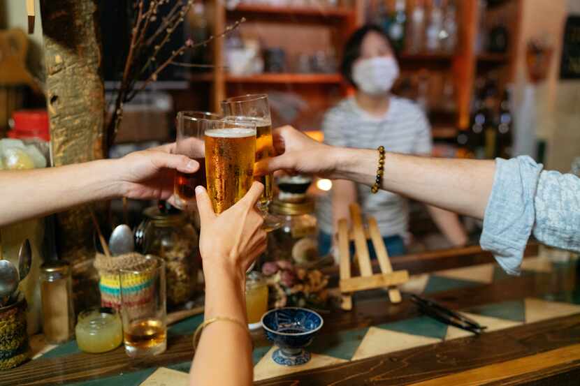 Foto de primer plano de personas que animan con cerveza en bar con medidas de protección de...