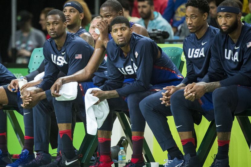 Harrison Barnes of the United States (far left) watches the game from the bench as they US...