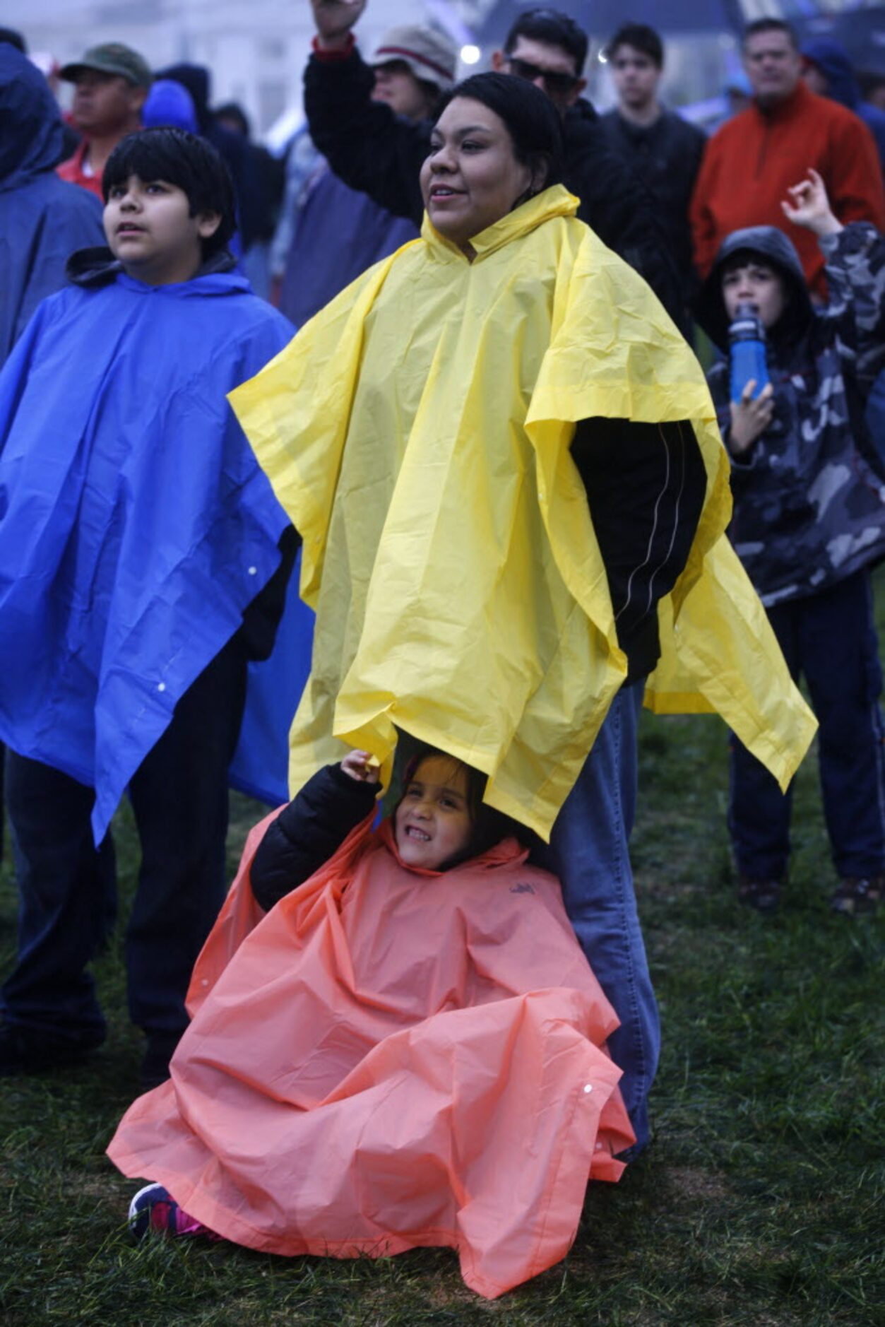 Catherine Acosta, 6, gets shelter from the rain under her mother, Carmen Acosta's raincoat...