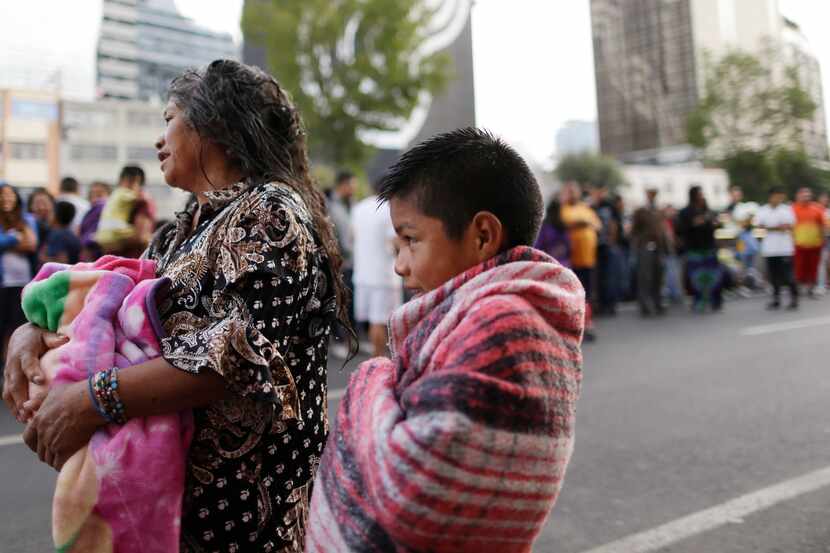People stand in the street after hearing an earthquake alarm, in Mexico City, Saturday,...