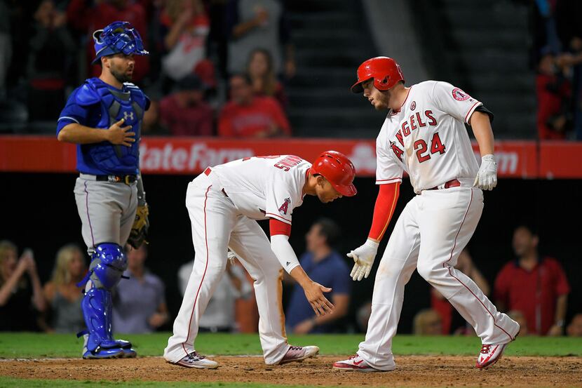 Los Angeles Angels' C.J. Cron, right, is congratulated by Andrelton Simmons, center, after...