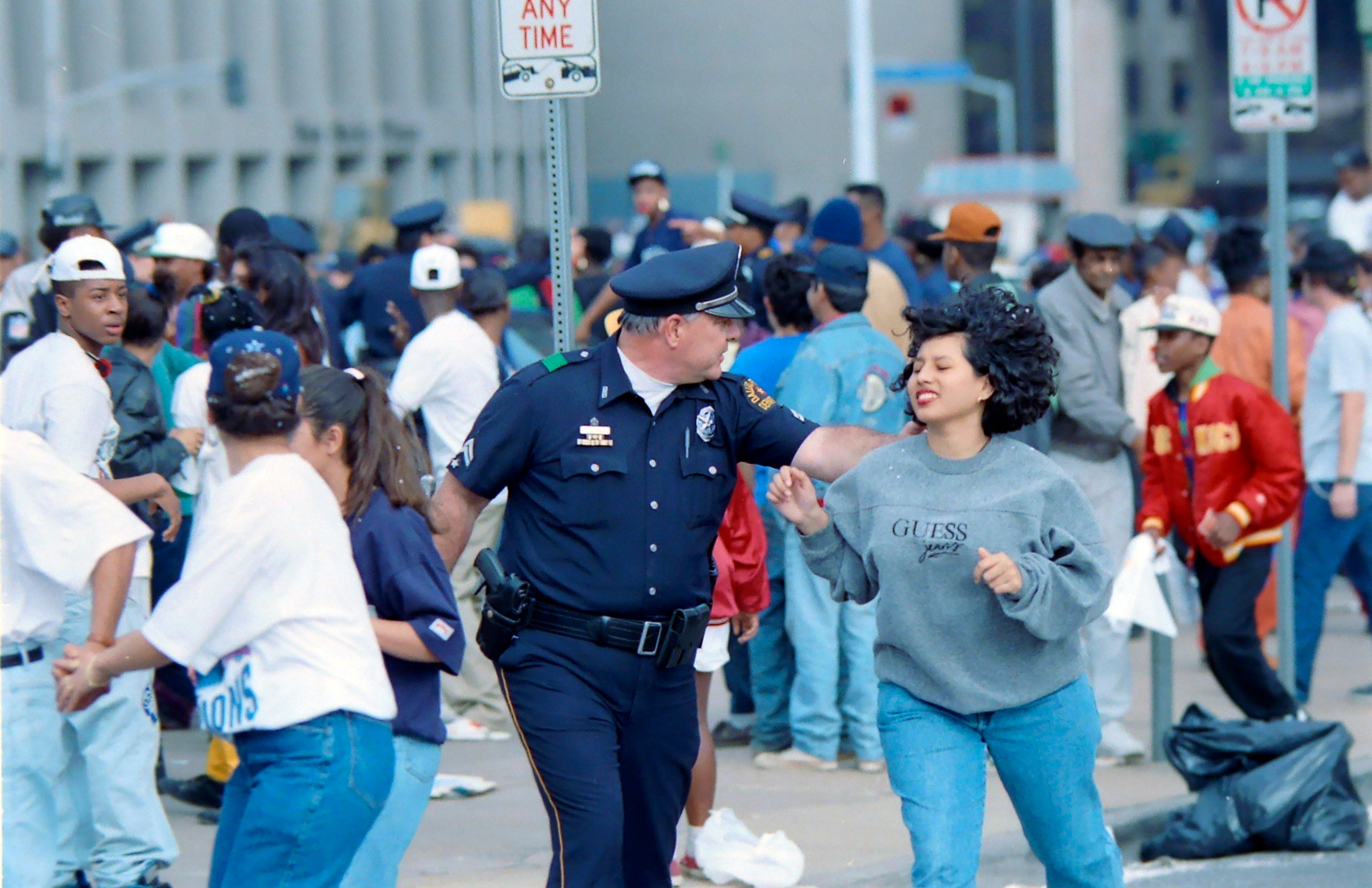 A Dallas Police officer moves a teenager away from violence that erupted along Commerce St...