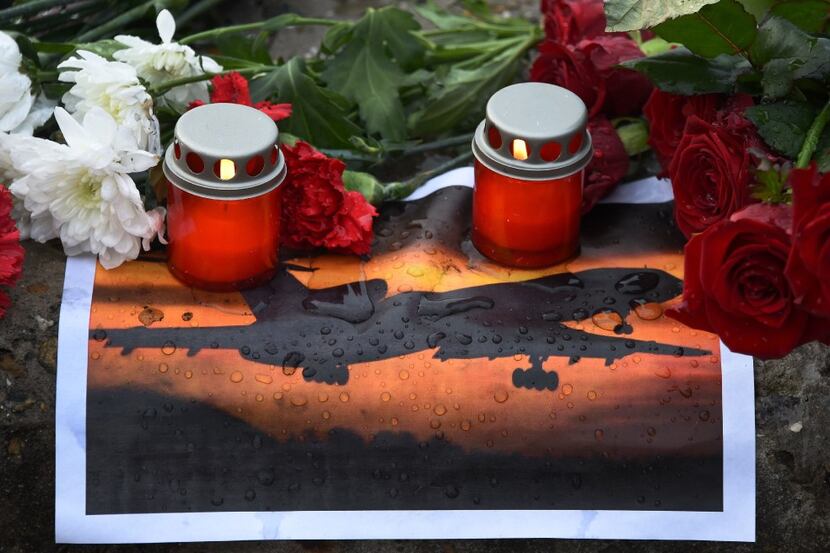 A picture shows candles and flowers layed next to a picture of an airplane at a memorial on...