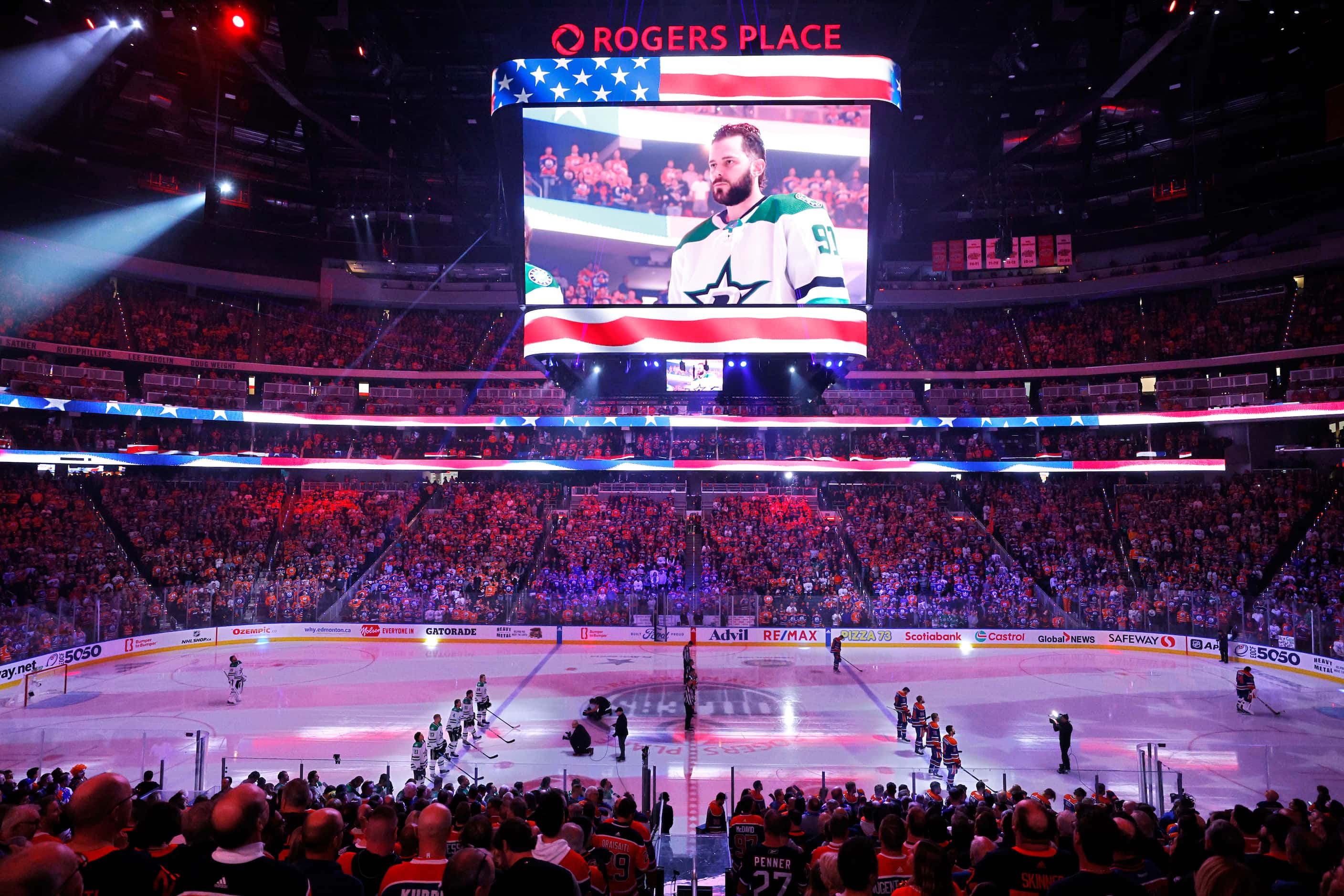 Dallas Stars and Edmonton Oilers players line up for the national anthem as the big screen...