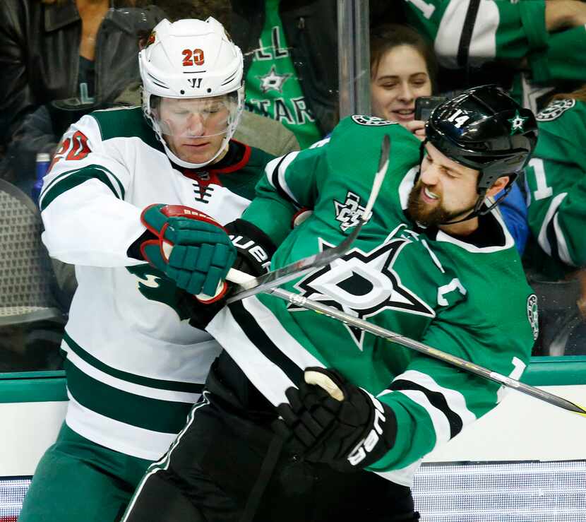 Dallas Stars left wing Jamie Benn (14) tries to break free from Minnesota Wild defenseman...