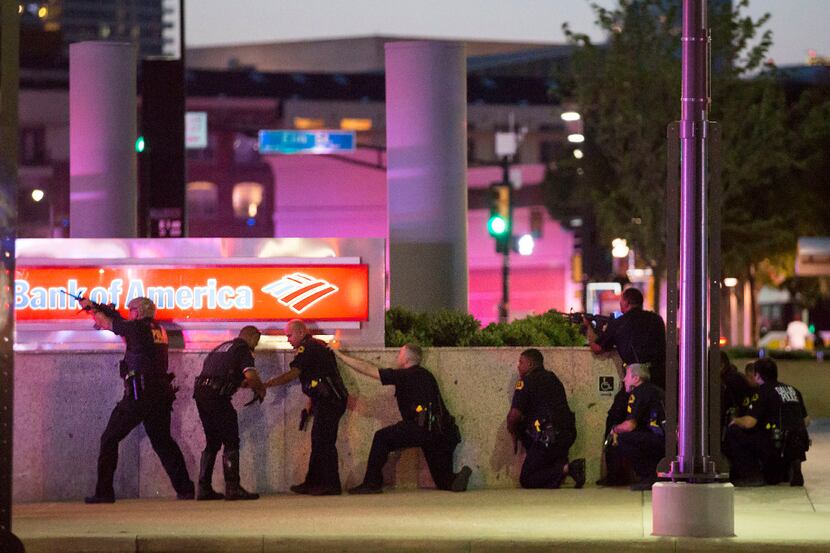 Dallas police took up positions along a wall at the corner of Lamar at Main streets as they...