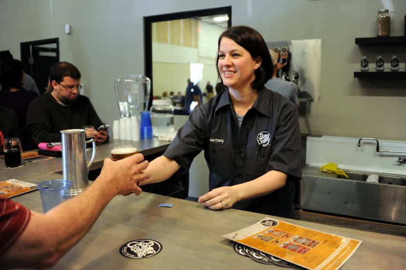 Bartender Courtney Ehinger hands a guest beer at the opening of Bitter Sisters Brewing...