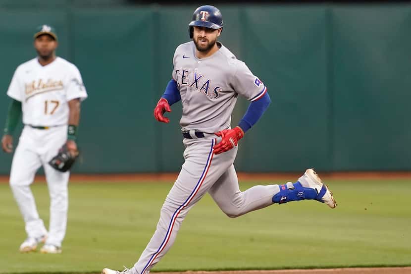 Texas Rangers' Joey Gallo, right, rounds the bases after hitting a home run as Oakland...