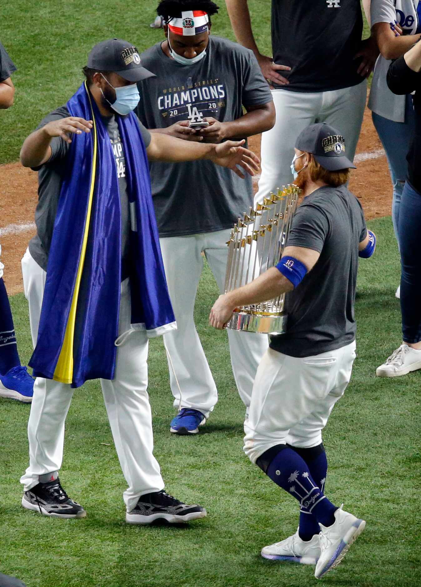 Los Angeles Dodgers third baseman Justin Turner (right, with trophy) receives a hug from...