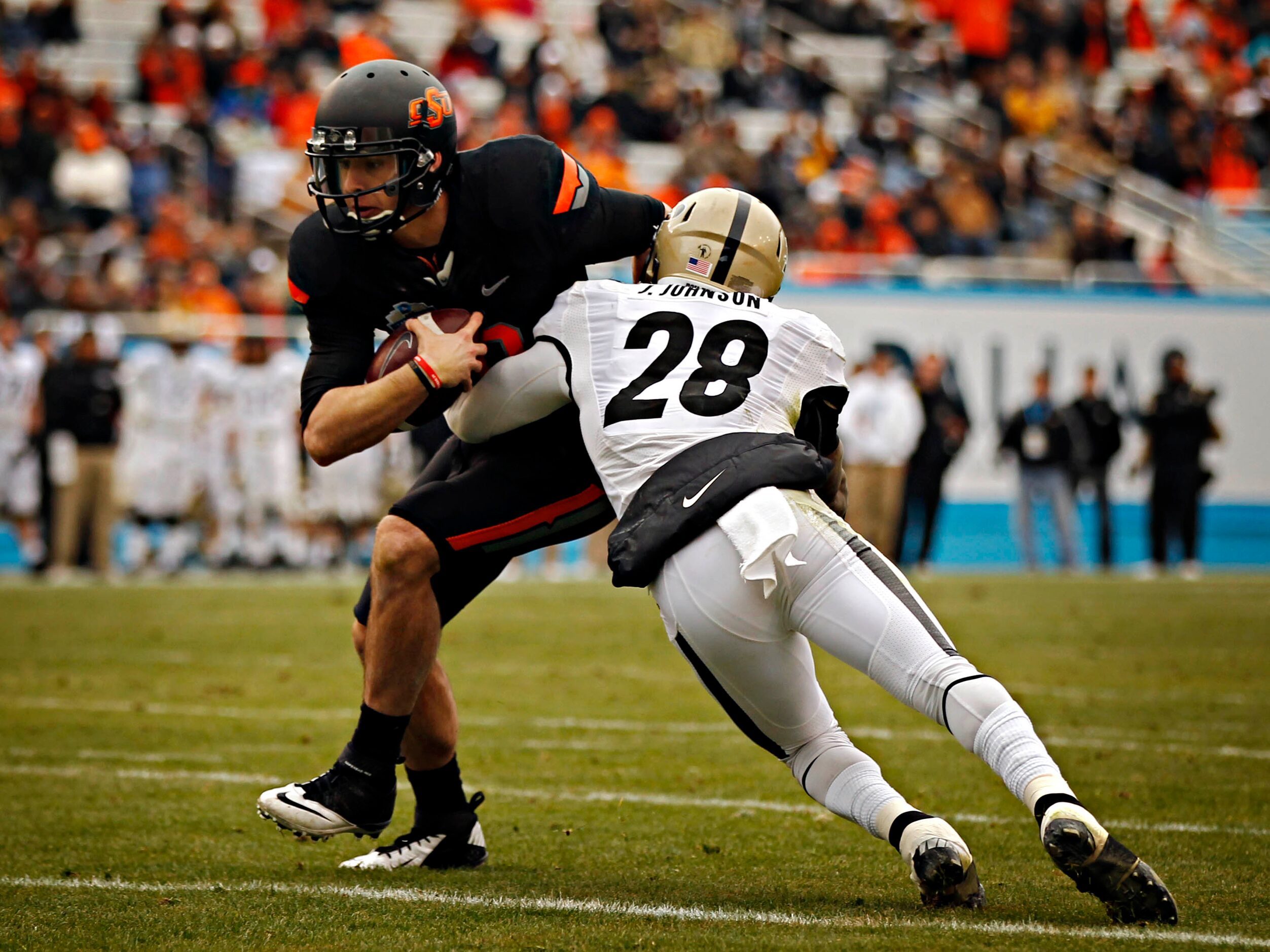 Oklahoma State Cowboys quarterback Clint Chelf (10) tries to evade a tackle by Purdue...