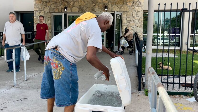 A man grabs cold water bottle from cooler during a hot day at OurCalling facility in Dallas.