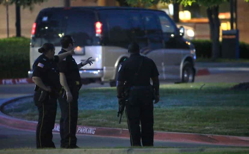 Police officers stands guard at a parking lot near the Curtis Culwell Center where a...