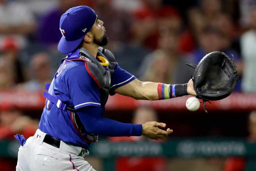 Texas Rangers catcher Robinson Chirinos can't get a glove in a infield fly hit by Los...