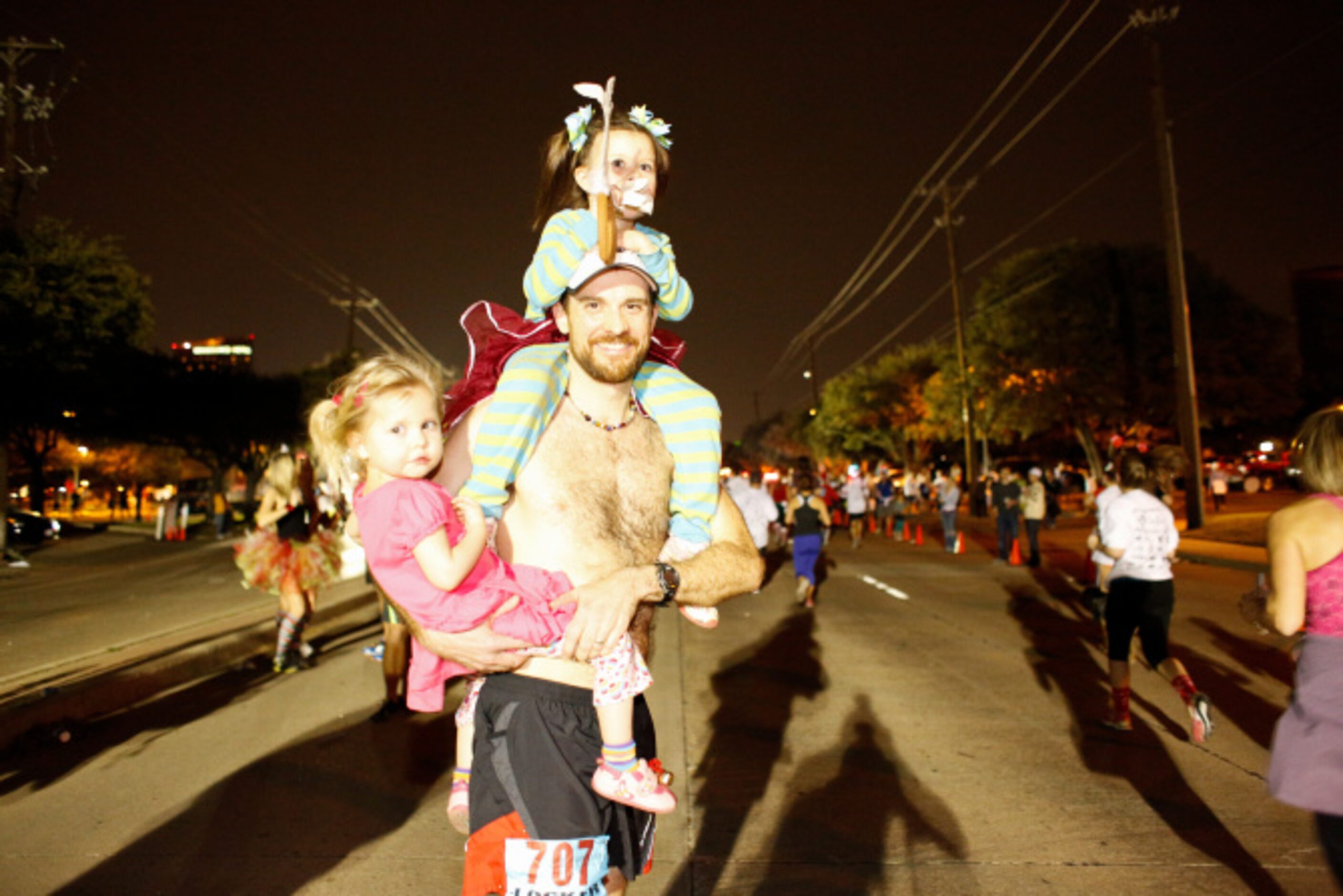 Matthew Crownover carries his daughters Ludia, 3, and Miriam, 5, top, after running in the...