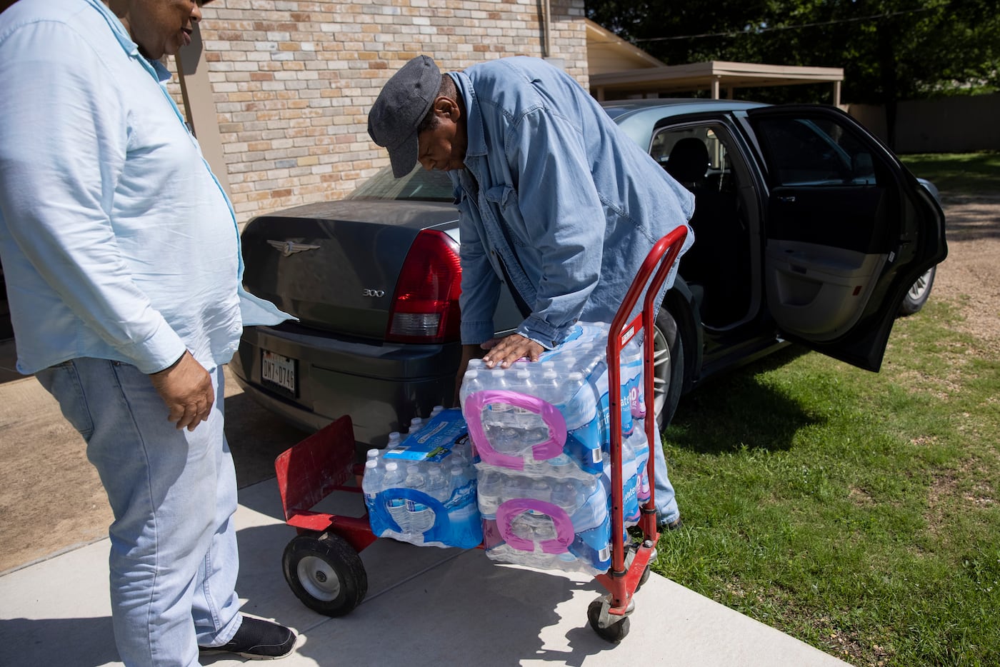 Jerone Roy (right) helps brother Deacon Bert Roy III load cases of water to distribute...