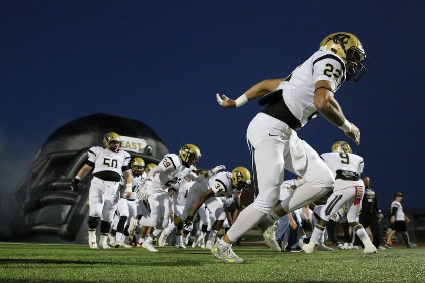 Plano East players run onto the field before a high school football game between Plano East...