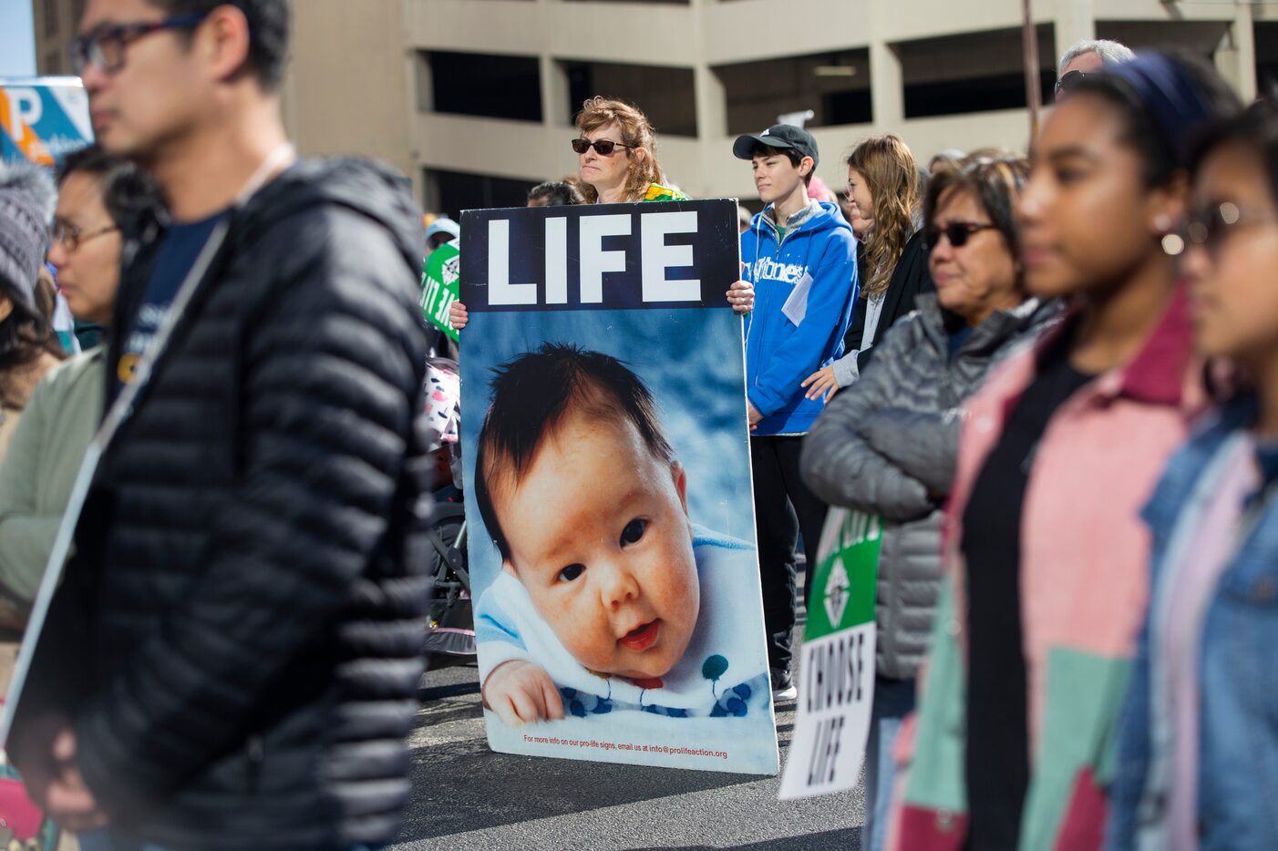 Colleen Sullivan (center) from Frisco holds a sign after marching from the Cathedral...