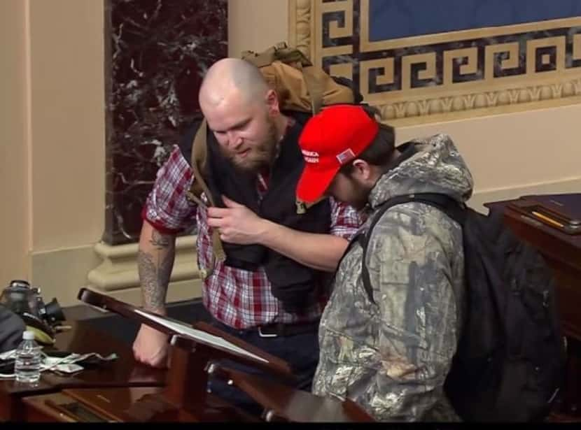 Joshua Johnson, left, inside the U.S. Senate chamber on Jan. 6, 2021.