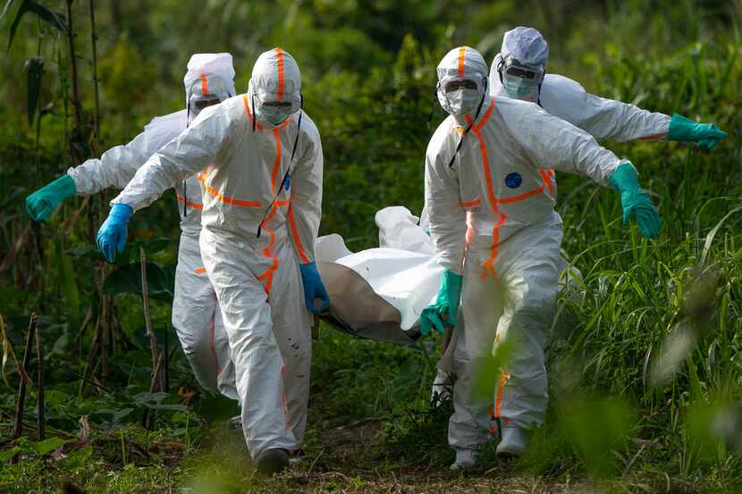 Burial workers dressed in protective gear carried the remains of an Ebola victim in July in...