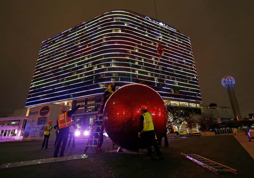 Workers install a giant red Christmas ornament outside the Omni Dallas Hotel in Dallas,...