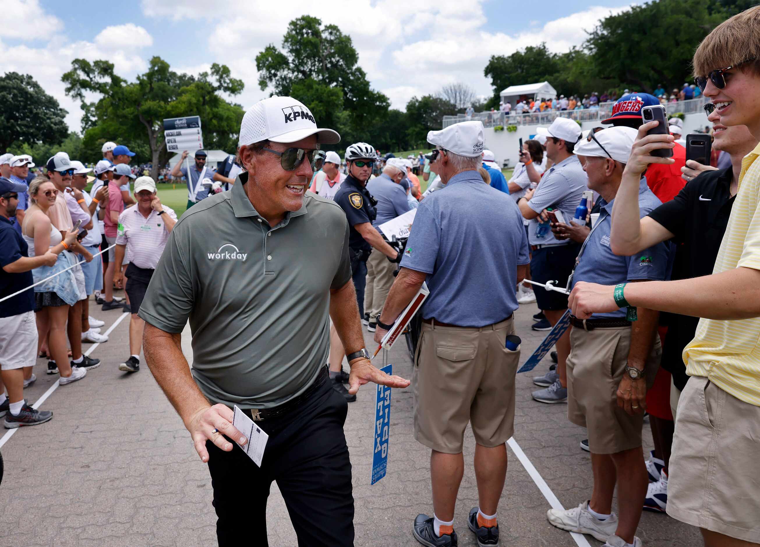 Professional golfer Phil Mickelson smiles at fans as he finishes his day with a 3-over, 73...