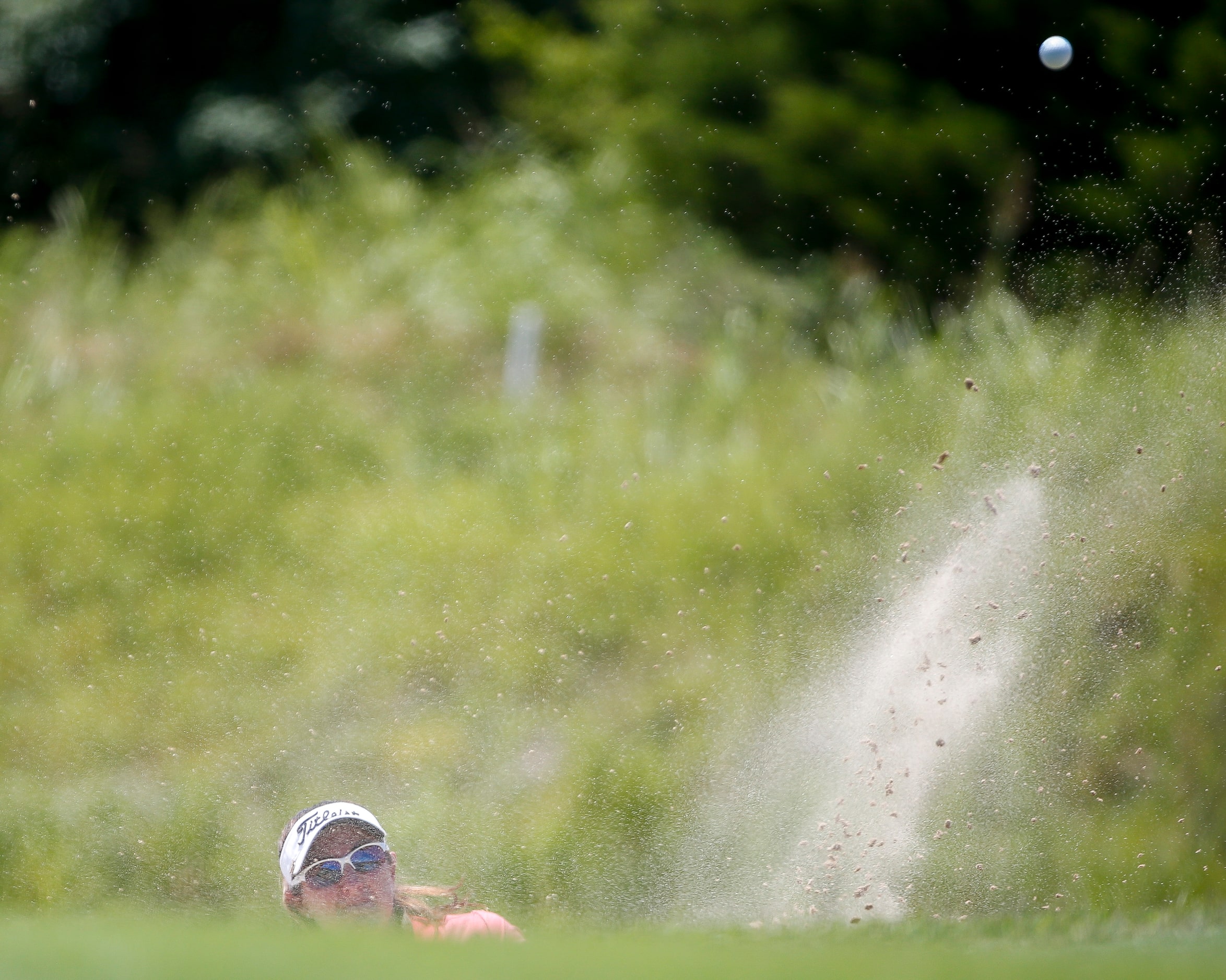 Professional golfer Amelia Lewis plays a shot out of the 17th green side bunker during round...