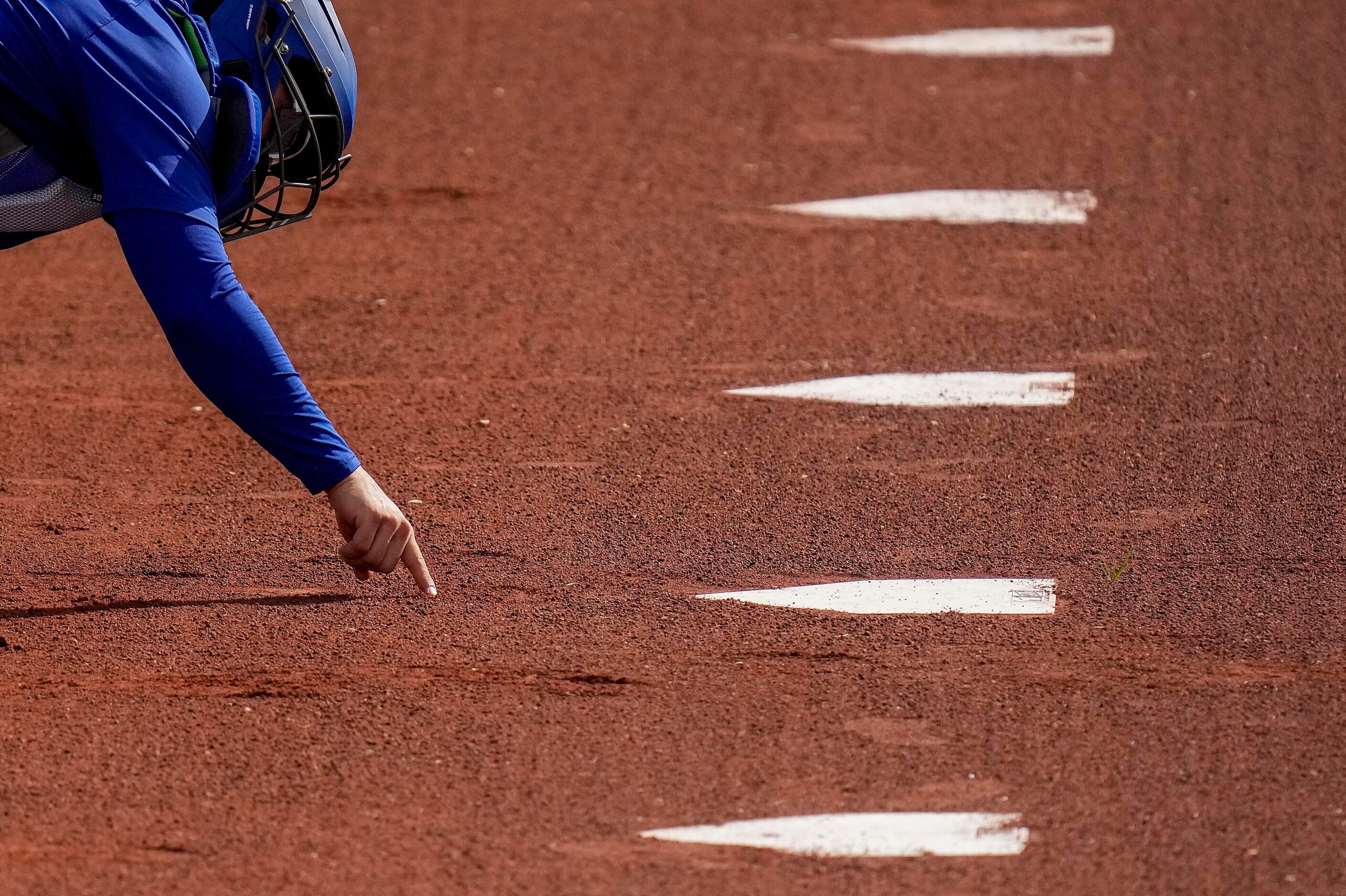 Texas Rangers catcher José Godoy makes a mark in the dirt while catching in the bullpen...