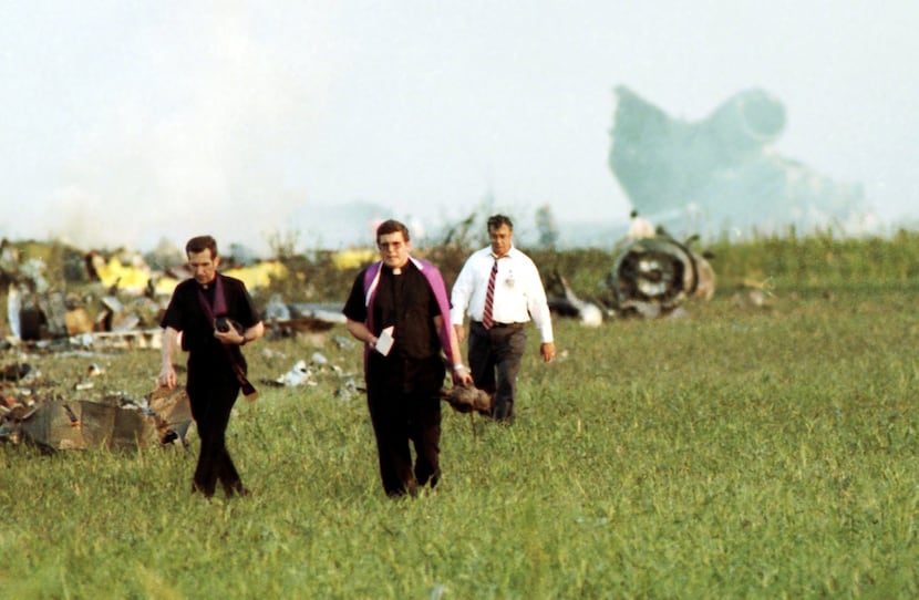 ORG XMIT: *S0413543147* 8/02/85 --- Two priests walking out the path of the Delta 191 crash,...