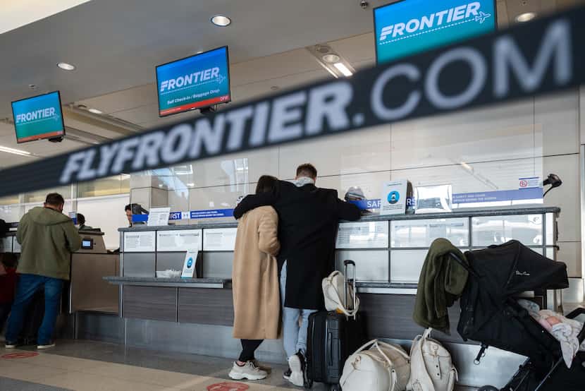 Passengers speak with Frontier customer service agents before boarding their flights at the...