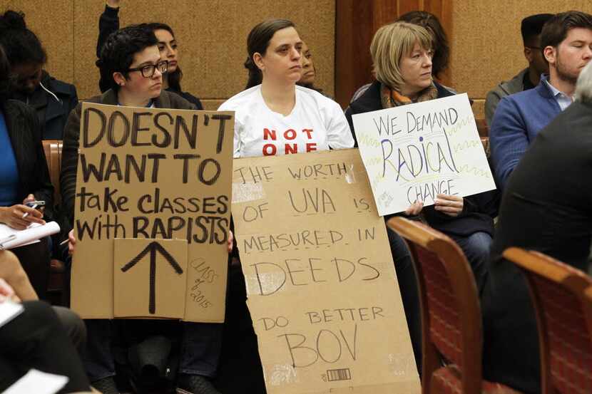 Members of the audience held signs during a board of visitors meeting about sexual assault...