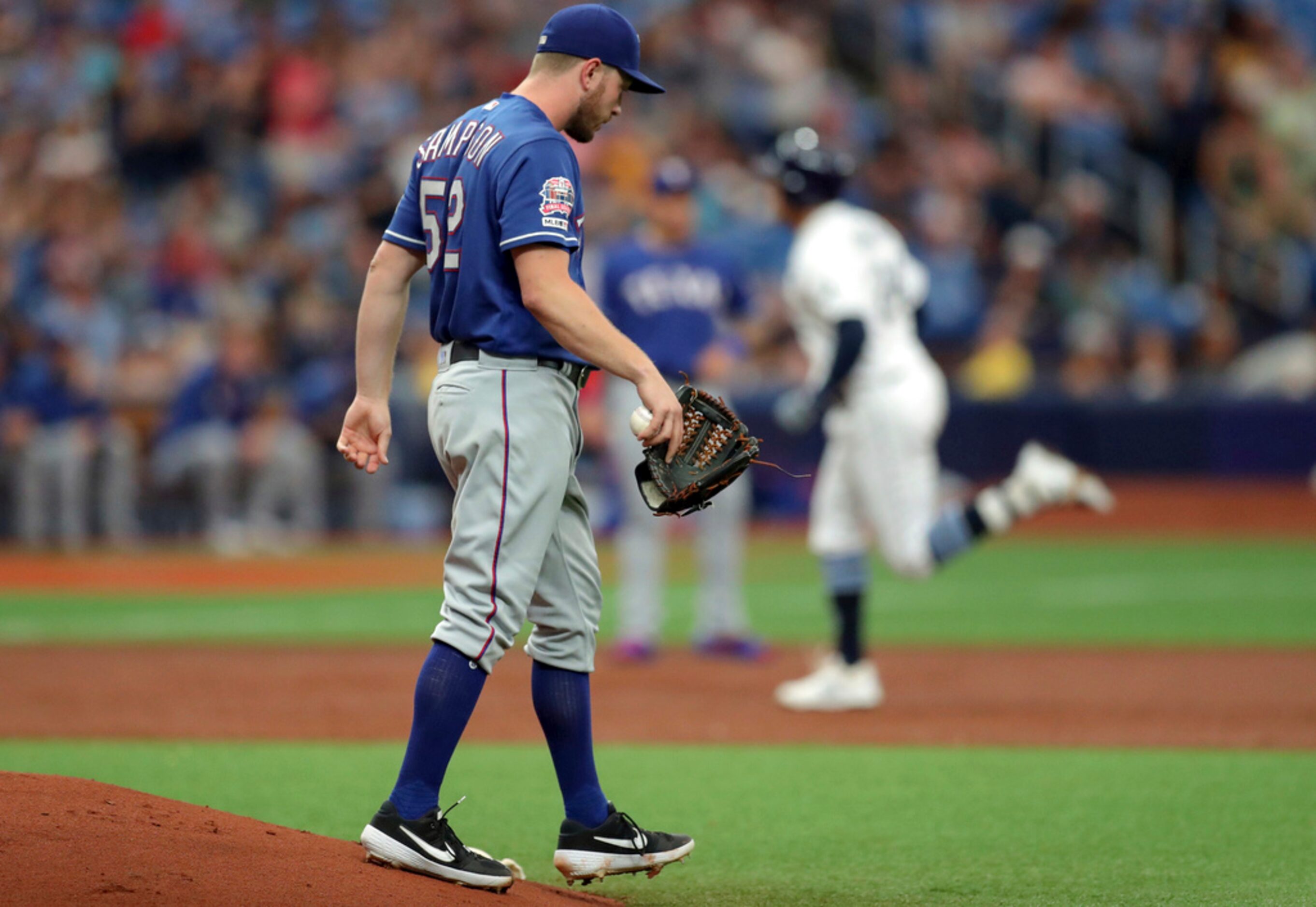 Texas Rangers starting pitcher Adrian Sampson, foreground, reacts after giving up a two-run...