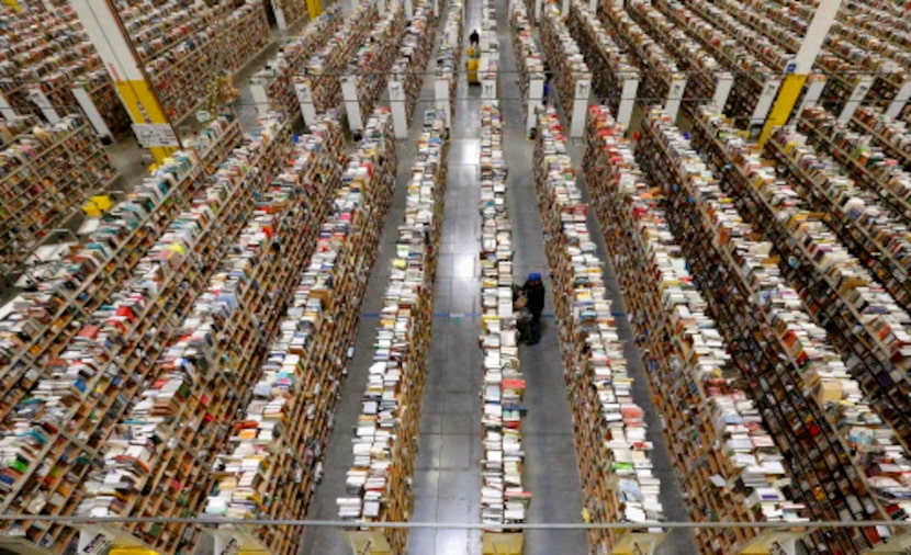 An Amazon employee stocks products along one of the many miles of aisles at an Amazon.com...