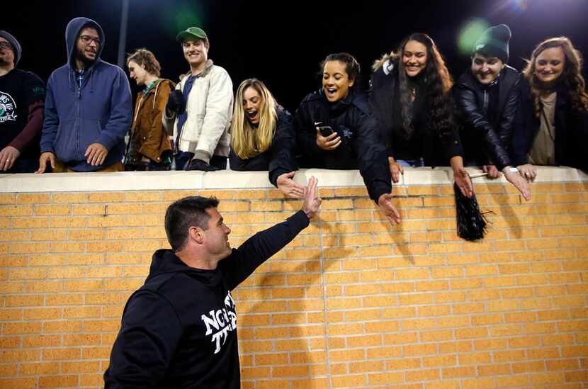 North Texas Mean Green head coach Seth Littrell slaps hands with students following their...