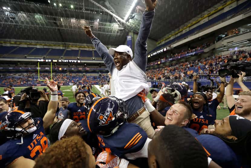 UTSA head coach Frank Wilson is lifted by his players as they celebrate their win over...