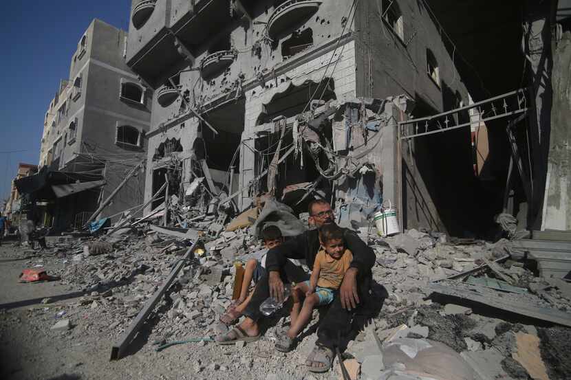 Palestinians sit outside their house following Israeli airstrikes in Rafah refugee camp,...